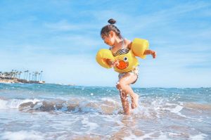 child playing in the water at the beach wearing water wings